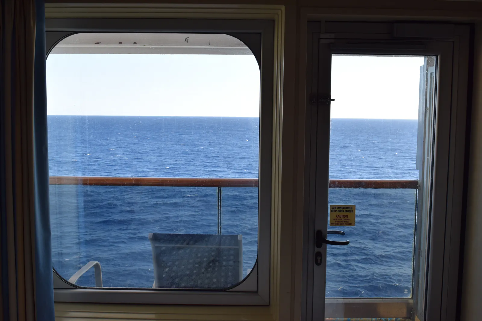 The view from my balcony cabin on Carnival Sunshine, looking through the window and balcony door to the open sea